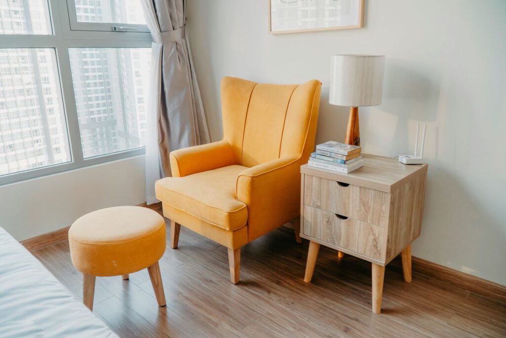 orange armchair with footrest next to window and end table