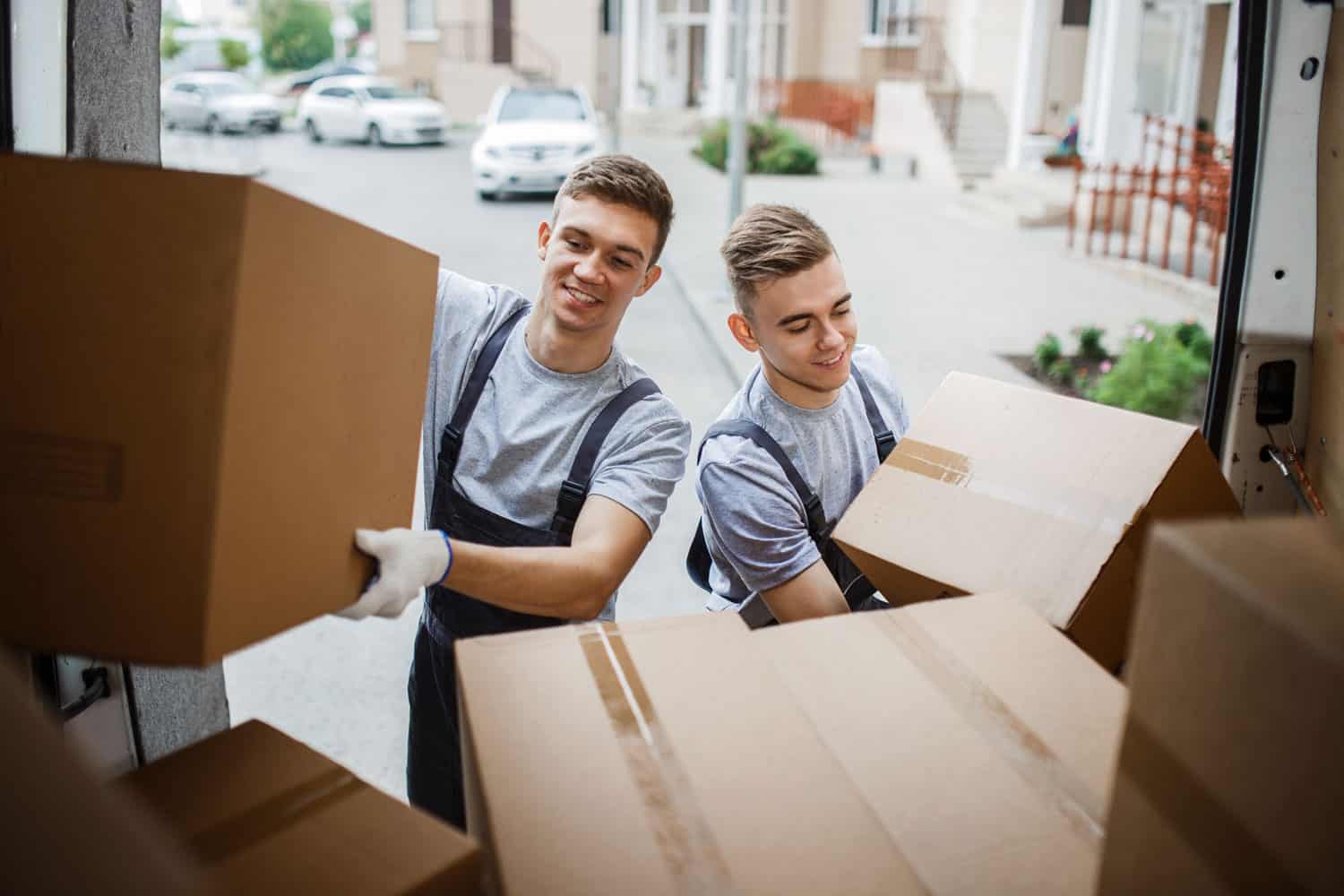 Two moving men bringing boxes to a moving truck for a furniture donation pick up